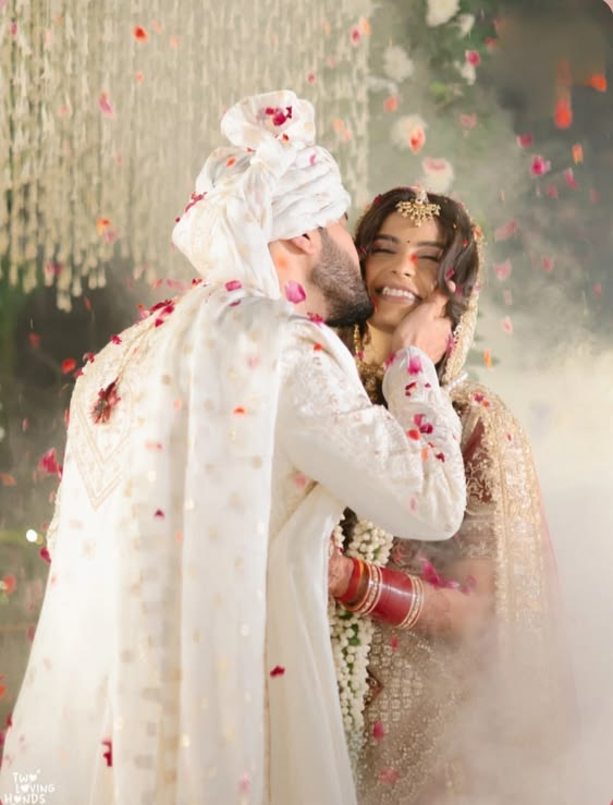 Groom kissing bride's cheek during rose petal shower